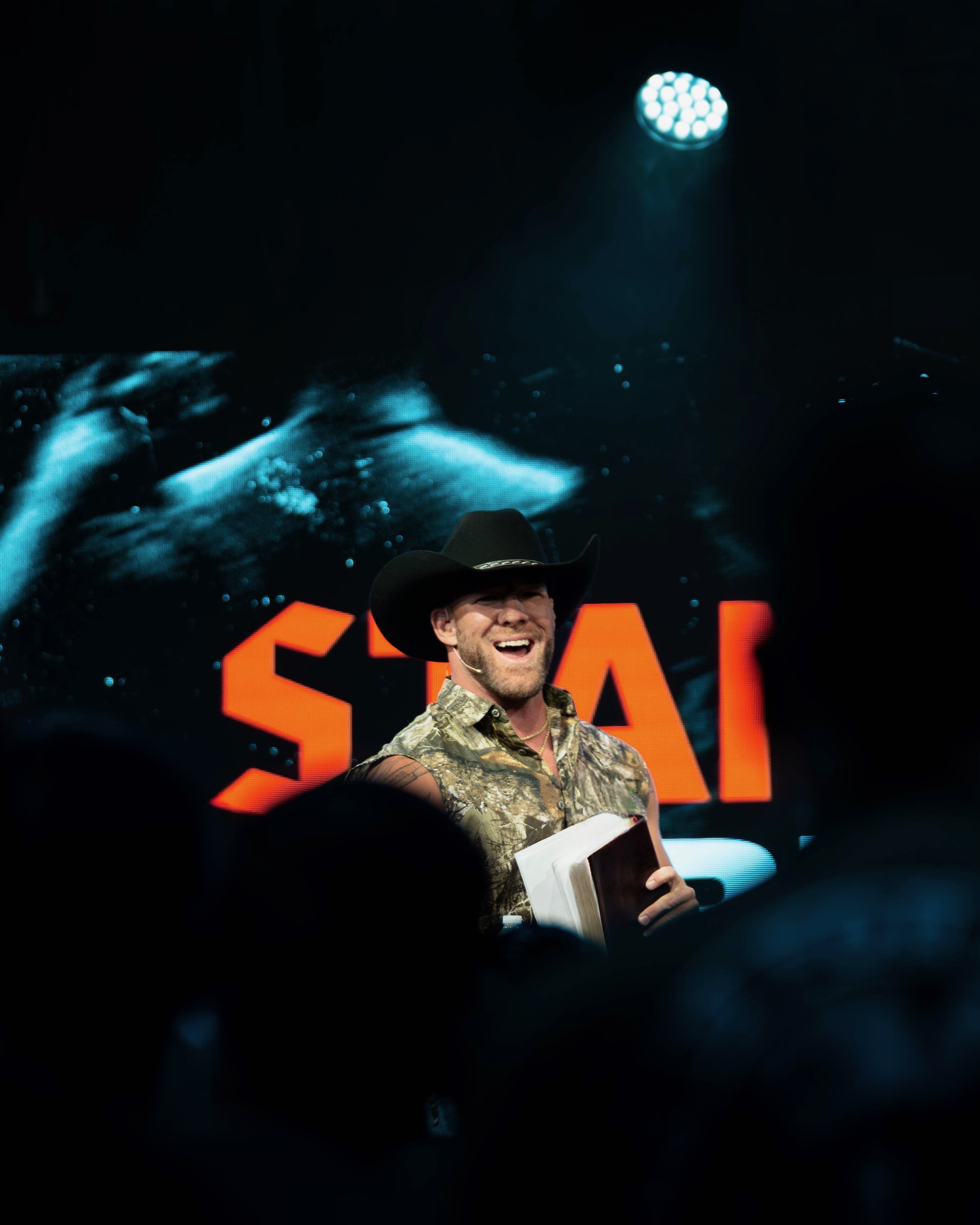 Mike laughing with open Bible on stage at Eleven22 Stand Firm